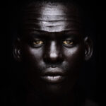 A man with black skin and yellow eyes.