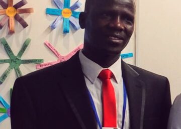 A man in a suit and tie standing next to paper flowers.